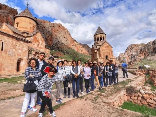 Grand groupe de touristes posant devant le complexe du monastère de Noravank