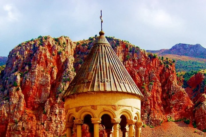 Gros plan sur le dôme du monastère de Noravank se détachant sur de spectaculaires falaises de roche rouge